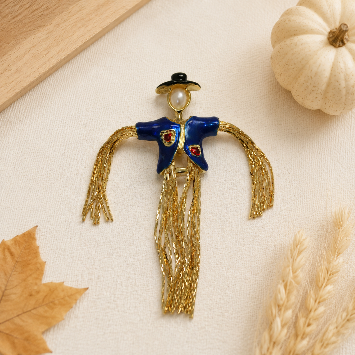 Gold-plated enamel scarecrow brooch with pearl face on white background