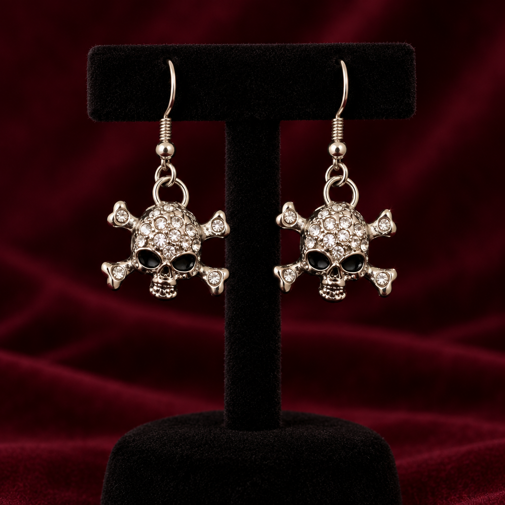 Skull earrings on black velvet display, deep red background